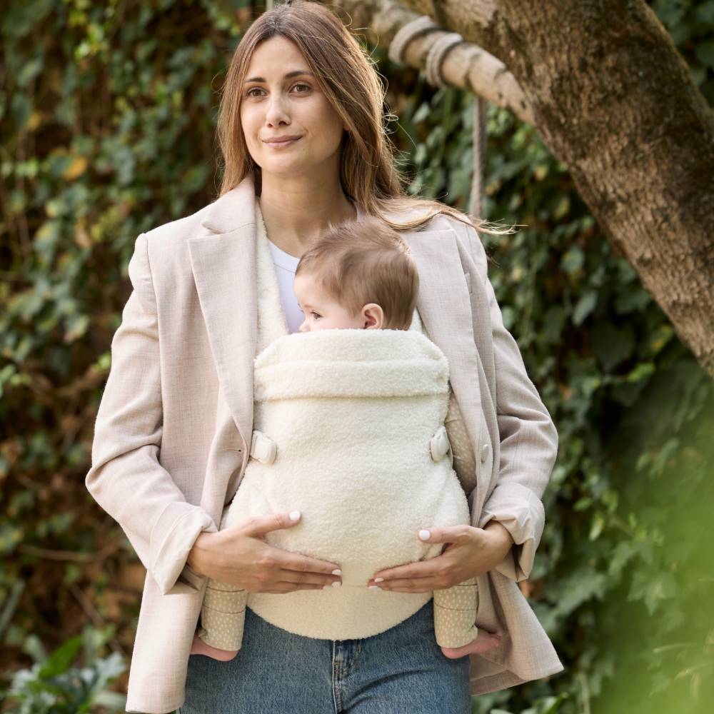 Woman holding a baby in a carrier outdoors
