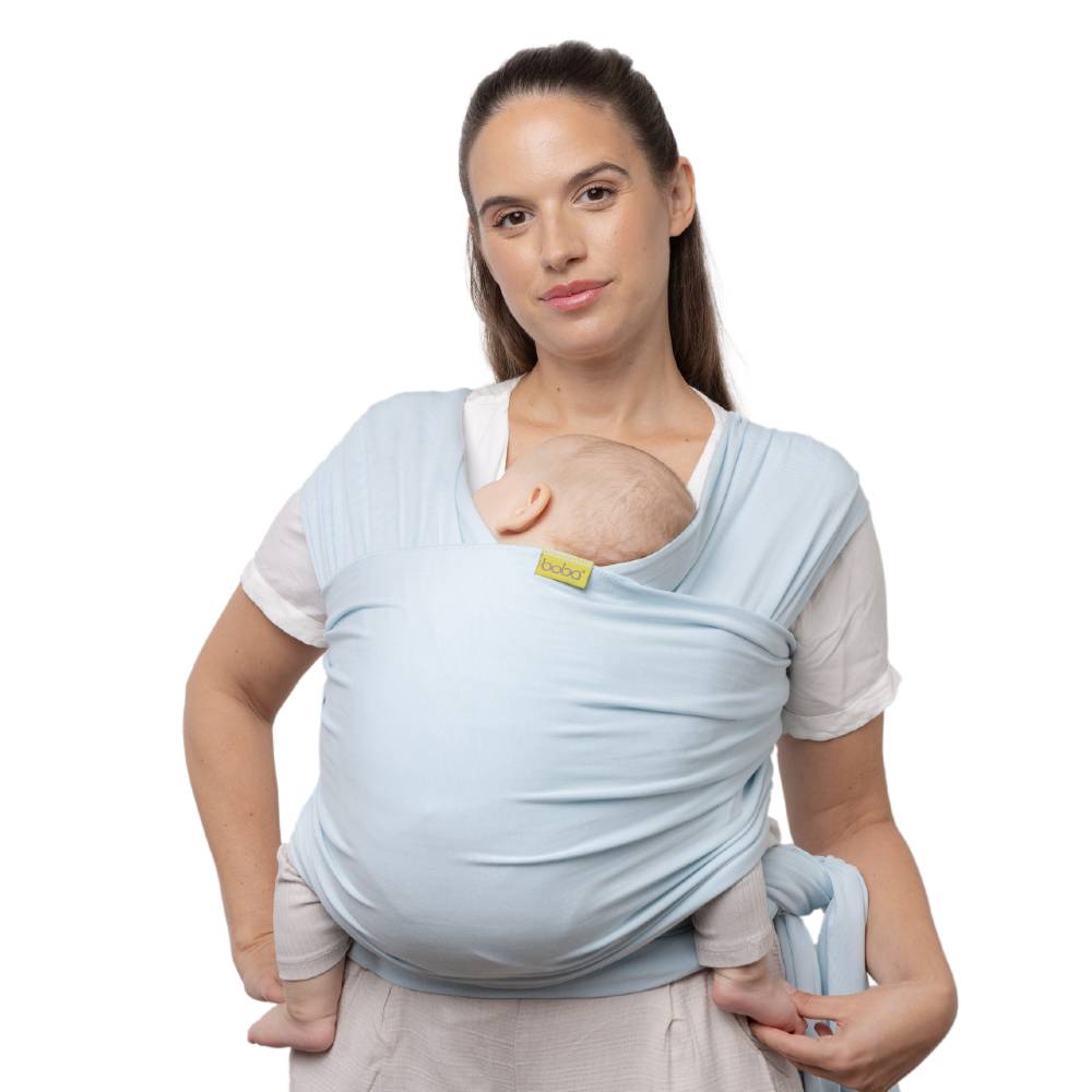 Woman wearing a light blue baby wrap carrier on a white background