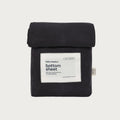 A folded black cotton bottom sheet with a white paper label reading 'babu basics bottom sheet' on a light gray background.