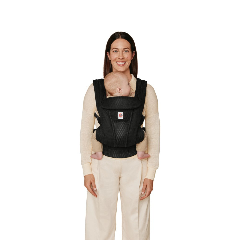 Woman wearing a baby in a black carrier on a white background