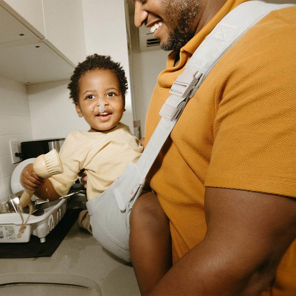 Man holding a child in a kitchen, both smiling