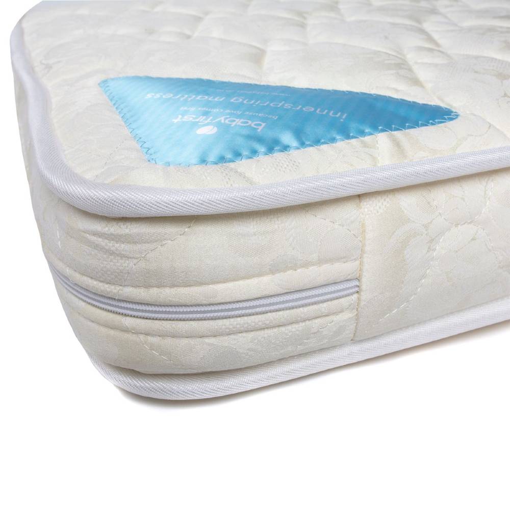 Close-up of a quilted mattress corner with a visible blue branded patch label on a white background.