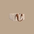 A rectangular storage basket with a beige and white houndstooth pattern, featuring two brown leather handles, set against a solid beige background.