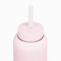 A close-up of a matte light pink bottle with a matching pink lid and a white cylindrical straw, set against a solid white background.