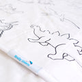 Close-up of a white quilted brolly sheet featuring black line drawings of dinosaurs, with a white fabric tag showing the brand 'Brolly Sheets'.