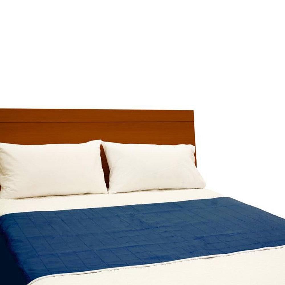 A bed with a dark brown wooden headboard, two white pillows, white bedding, and a navy blue quilted brolly sheet pad, shown against a plain white background.