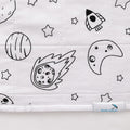 Close-up of a white quilted waterproof ped pad featuring a black line art space print with stars, planets, a moon, and a rocket. A small fabric tag at the bottom right reads 'Brolly Sheets'