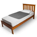 A wooden single bed frame with a slatted headboard shown with white bedding and a grey brolly sheet bed pad on a plain white background.