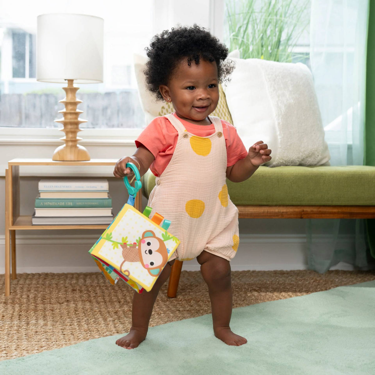 A baby holding a Safari Buddies Soft Book. 