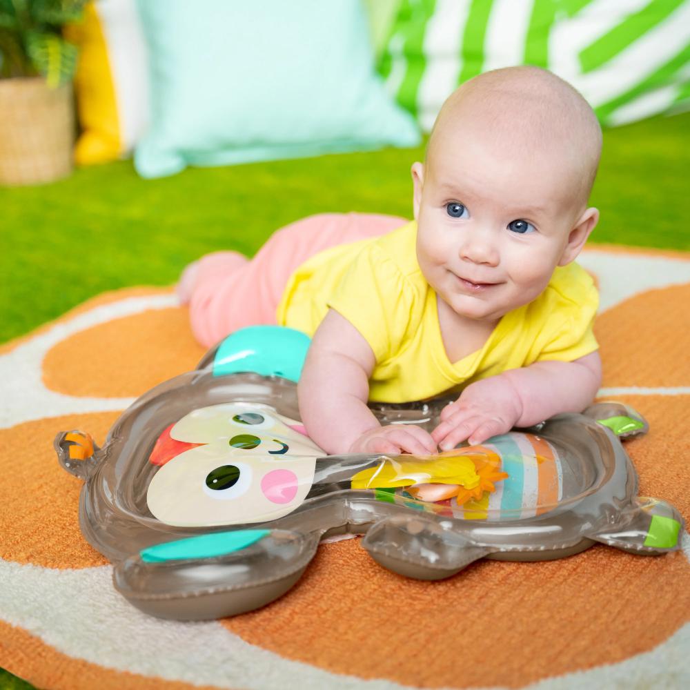 Baby playing with a colorful toy on a mat outdoors
