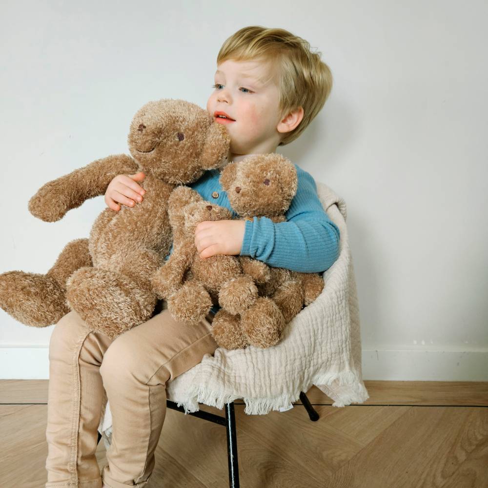 A young boy holding 3 Happy Horse Bear Bruno Soft Toys. 
