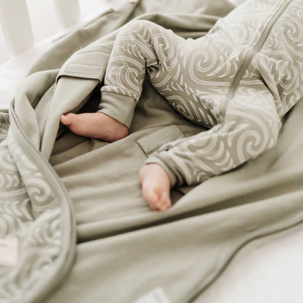 Baby in patterned outfit lying on a textured blanket