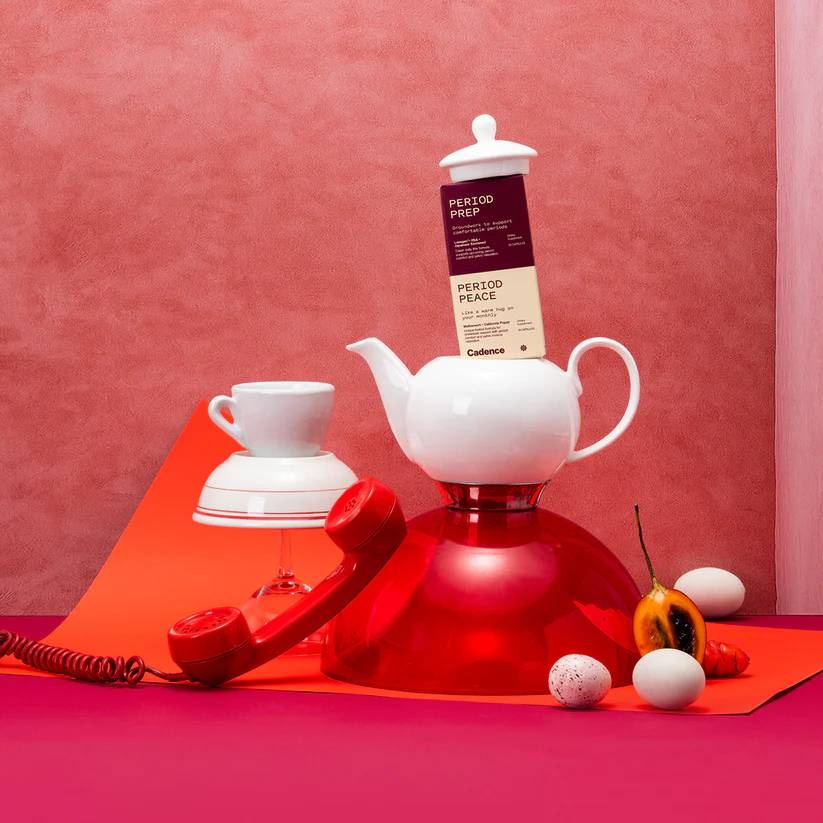 Product packaging on a red surface with a teapot and tea cup