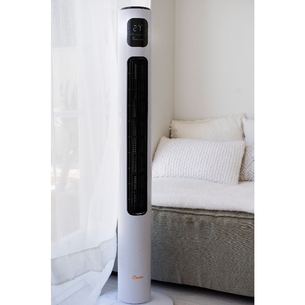 White tower fan in a room with a sofa and curtains