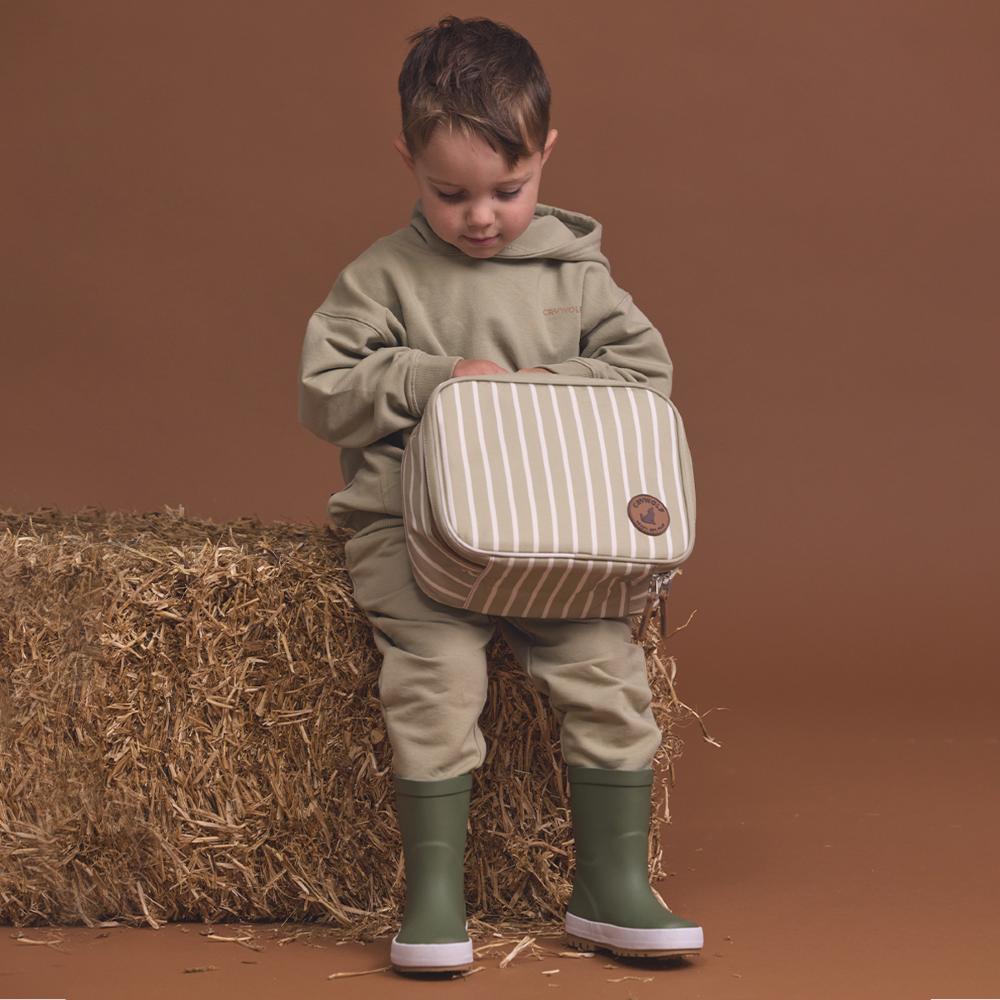 Child holding a striped lunch bag on a brown background