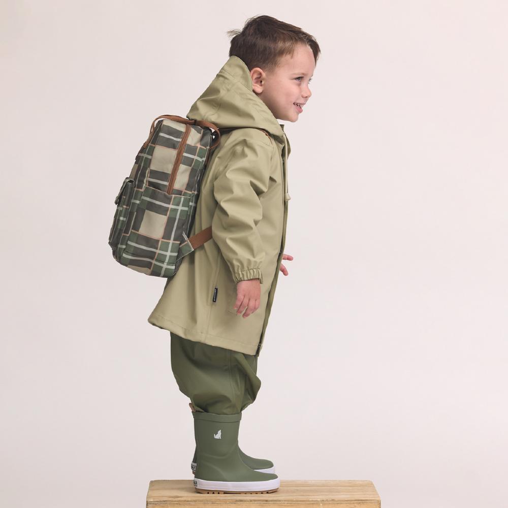 Child wearing a green coat, plaid backpack, and rain boots on a white background