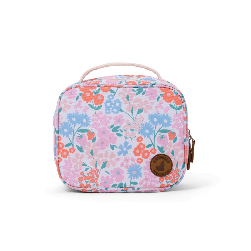 A lunch bag with a pastel floral print in pink, blue, and orange on a white background, featuring a top handle and a brown circular logo patch on the front.
