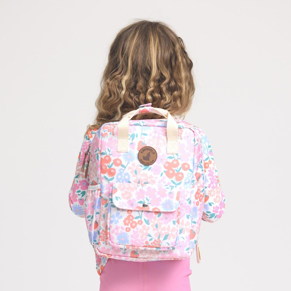 Child wearing a floral backpack on a plain background