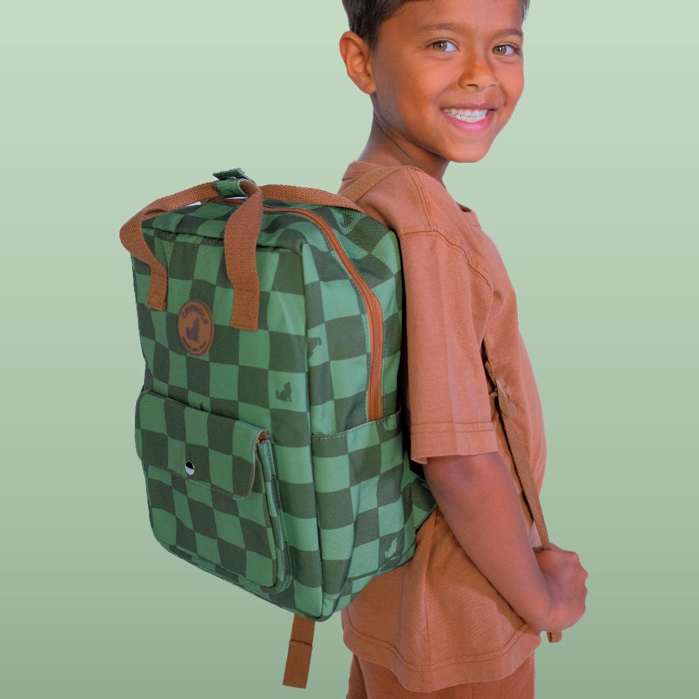 A smiling child wearing a green and dark green checkered backpack with brown straps, standing against a solid light green background.