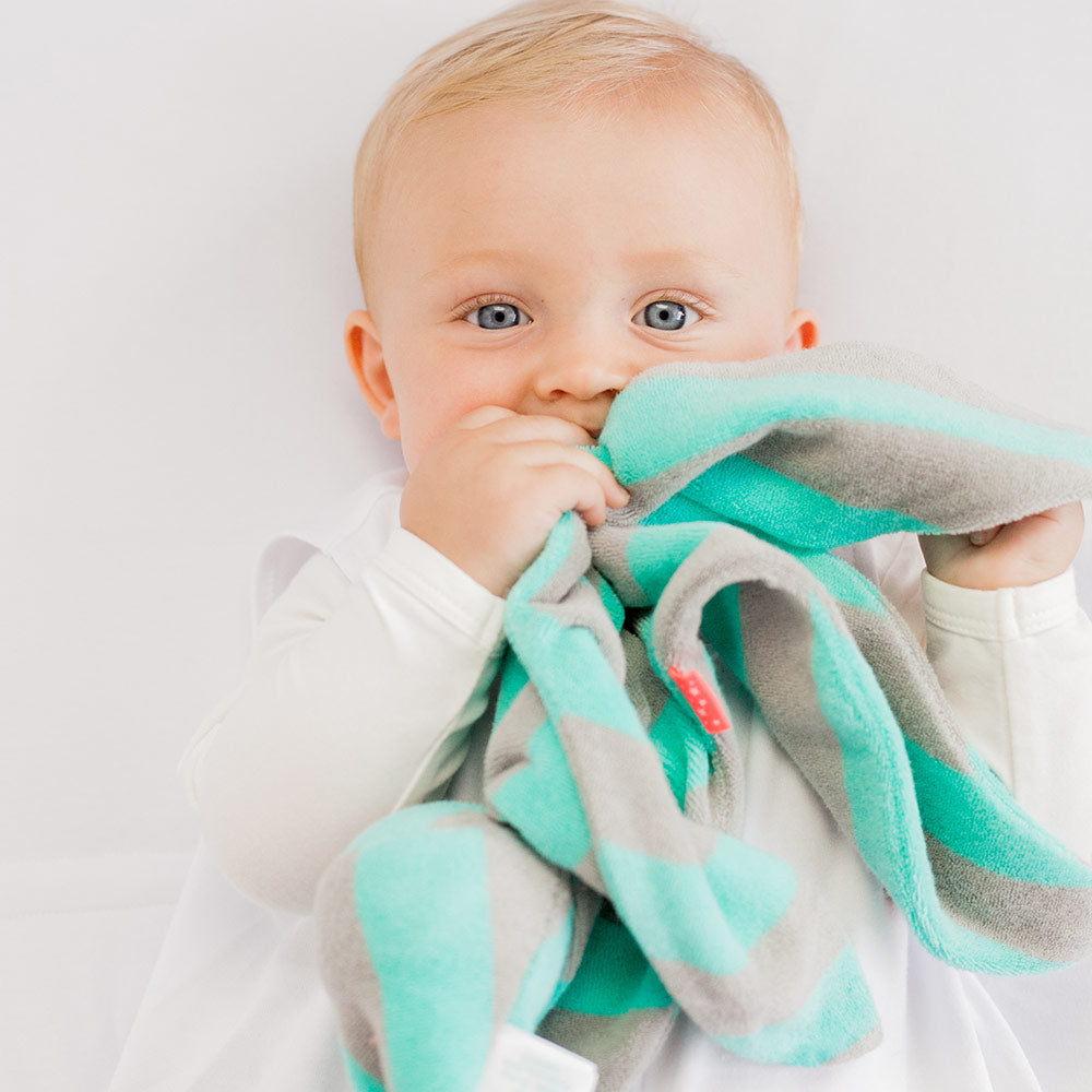 Baby holding grey and mint striped Fabby Cuski Comforter on a white background
