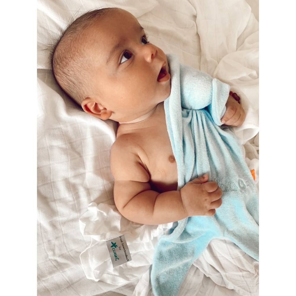 Infant in bed with Blue Cuskiboo comforter