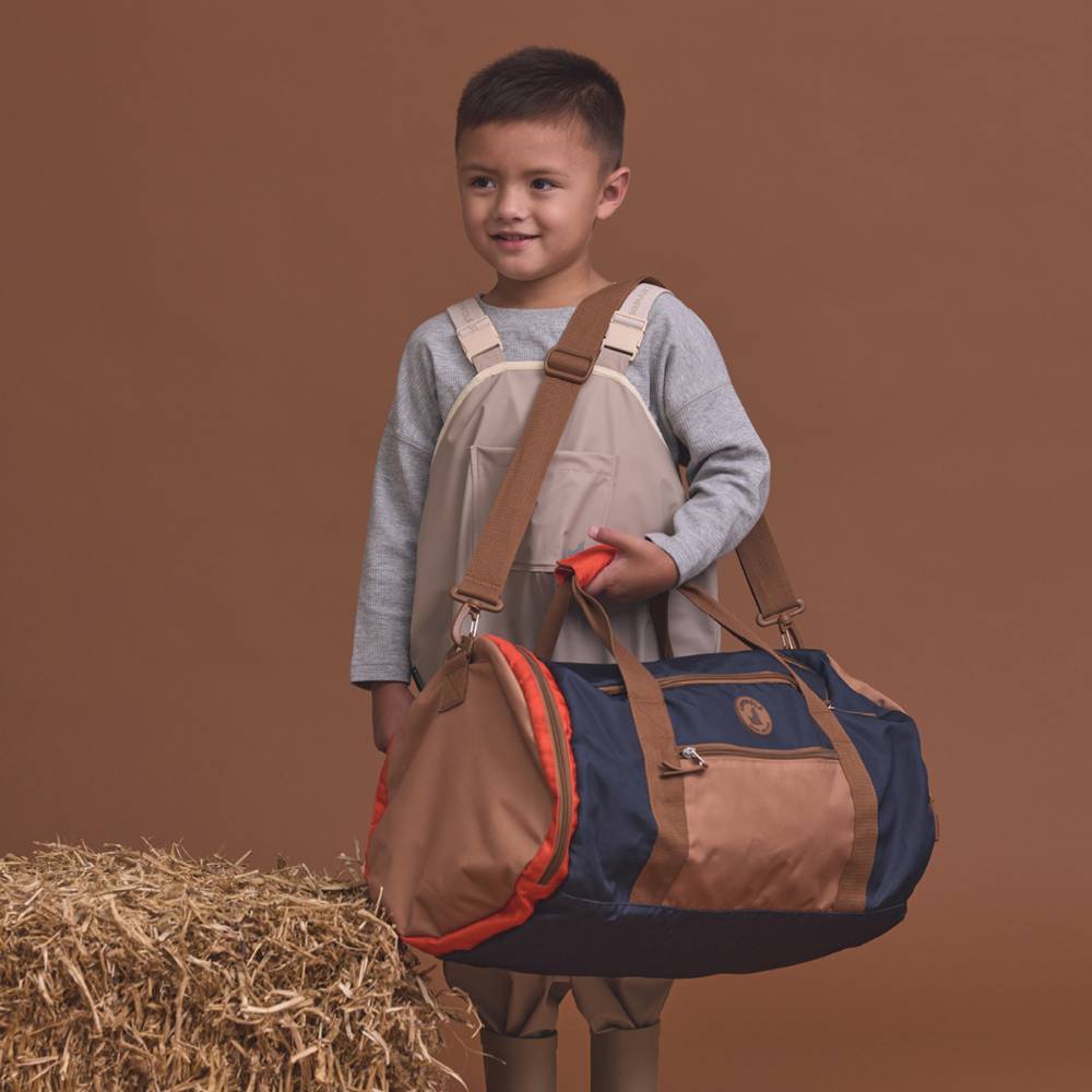 Child holding a duffel bag with a brown background