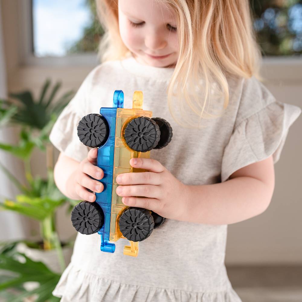 Child holding a toy car with blue and yellow body and black wheels.