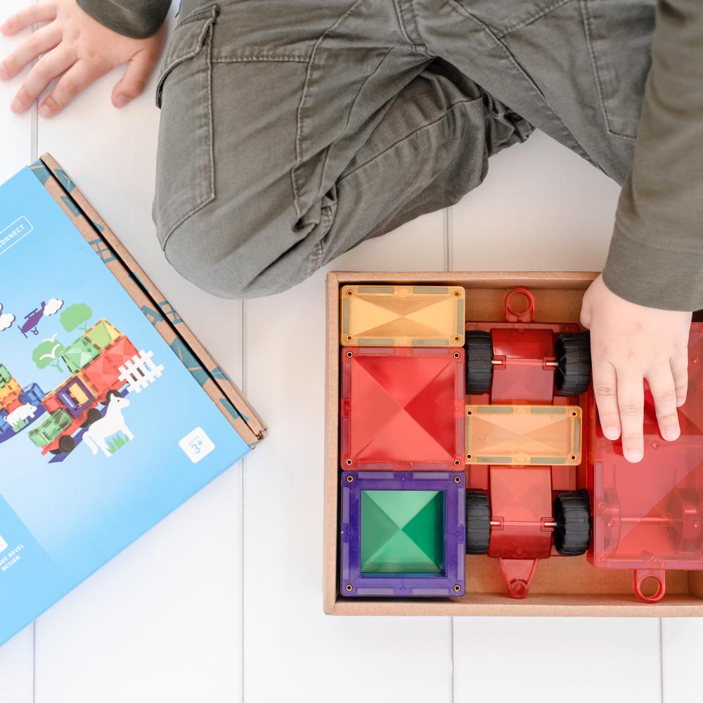 Child playing with colorful building blocks on a white floor.