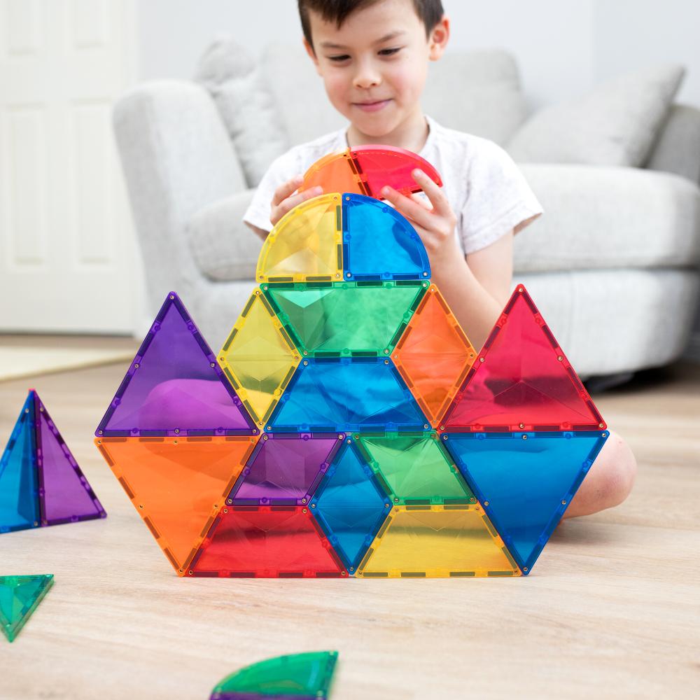 Child playing with Connetixcolorful magnetic building blocks on a light wooden floor.