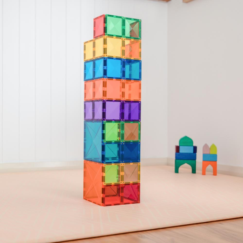 Colorful magnetic building blocks stacked on a wooden floor with a white wall background