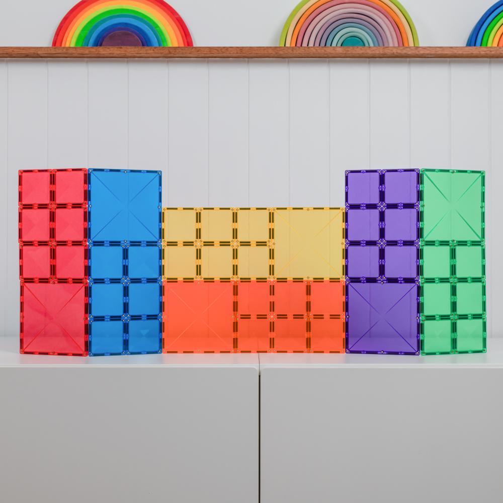 Colorful Connetix geometric building blocks on a light gray surface with a white grid background.