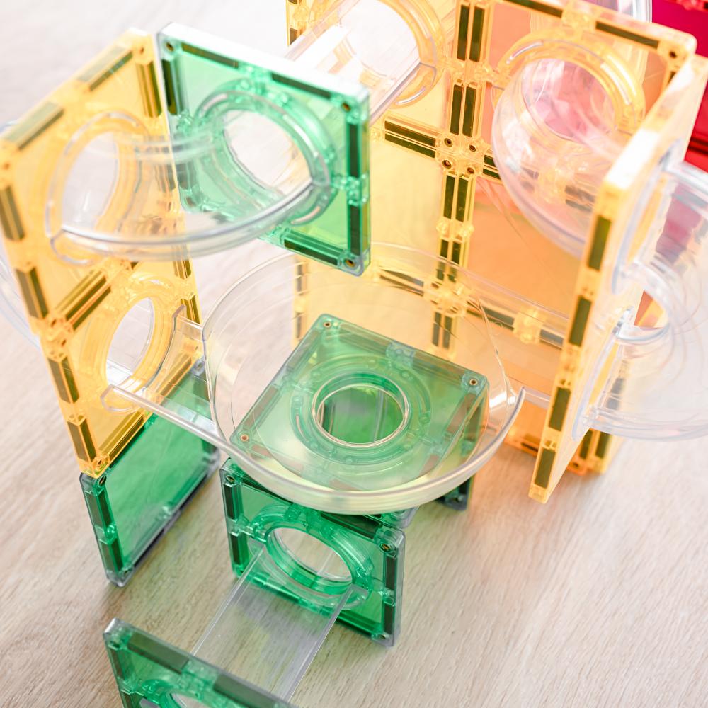 Transparent geometric building blocks ball run in green and yellow on a light wooden surface