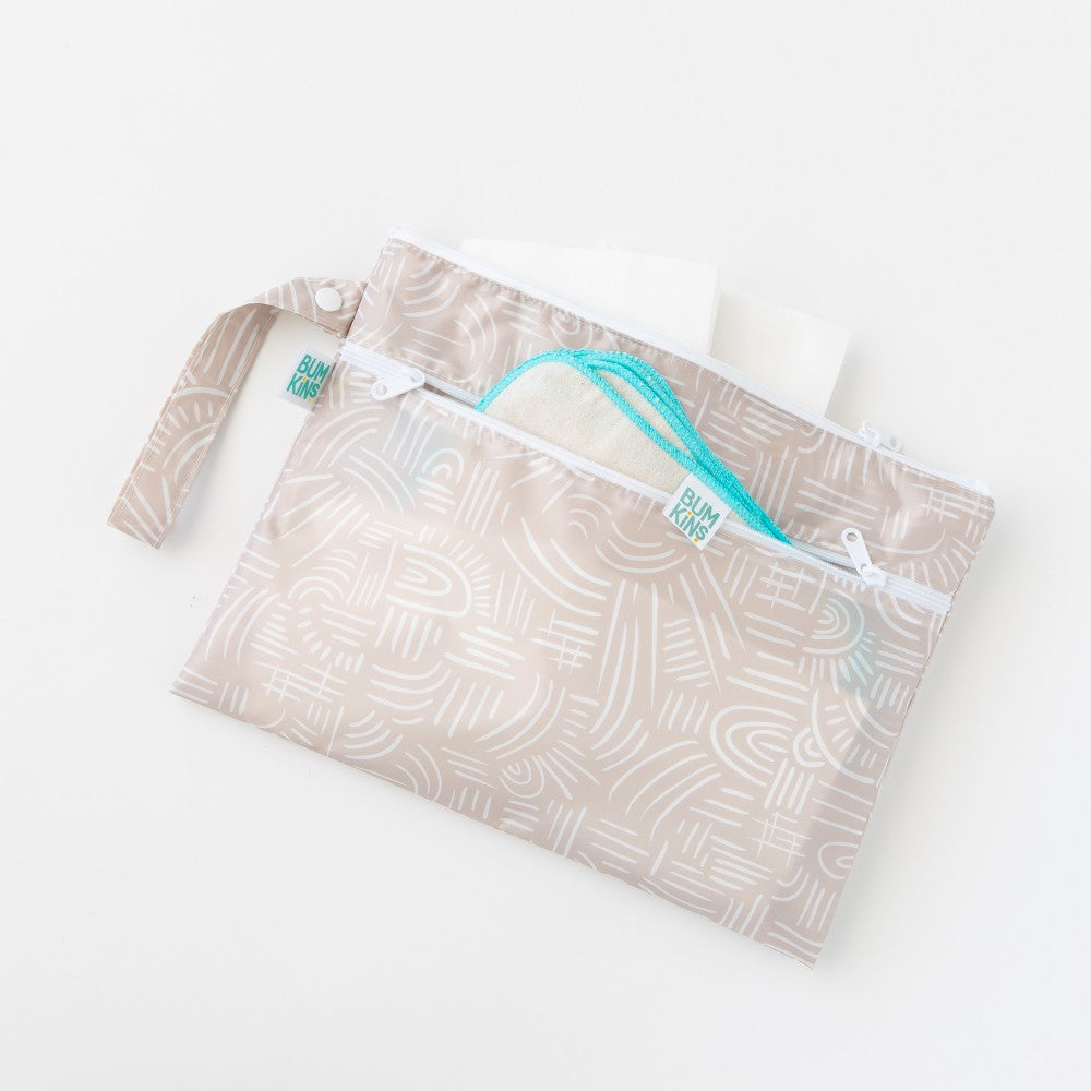 A reusable Nestling small wet bag with a matching wrist strap, featuring a light beige and white abstract line pattern. Filled with Bumkins cloth wipes.