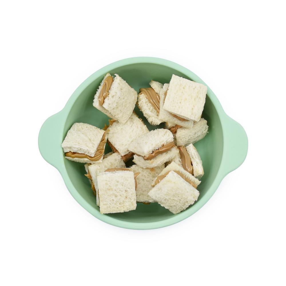 Green bowl filled with small sandwiches on a white background