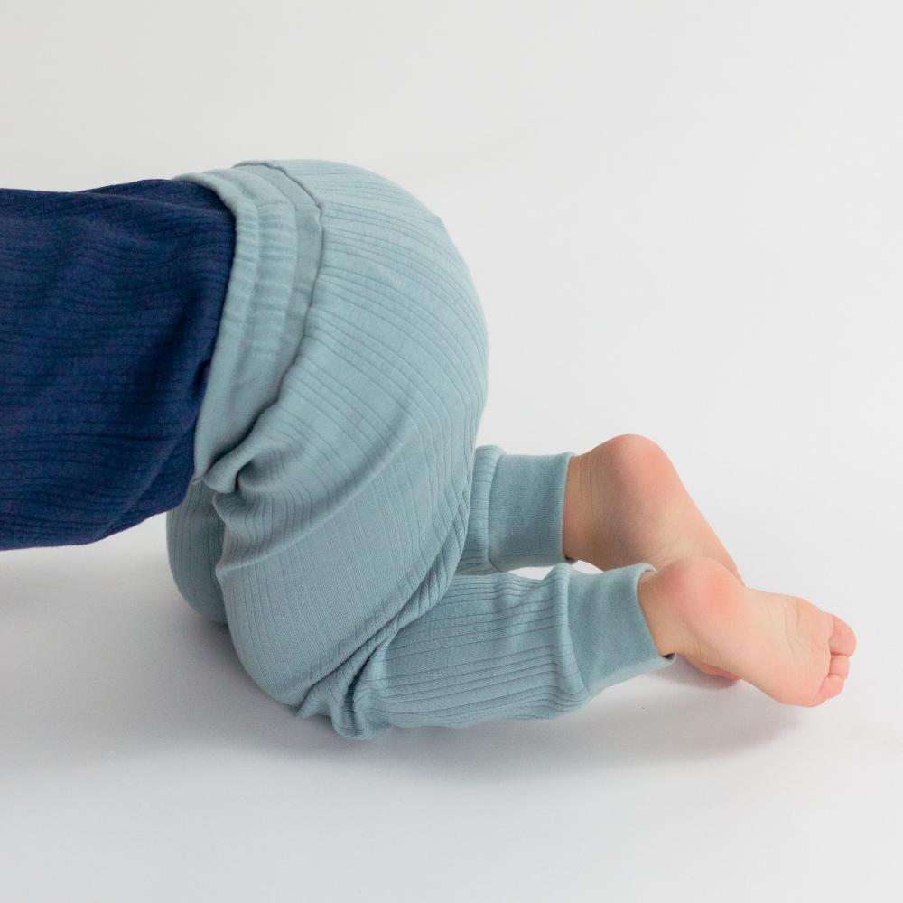Light blue baby leggings worn by a child on a white background