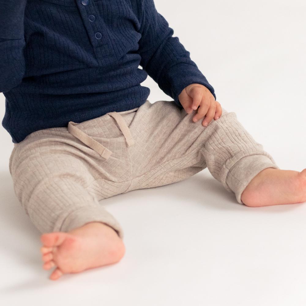 Child wearing navy shirt and beige pants on a white background