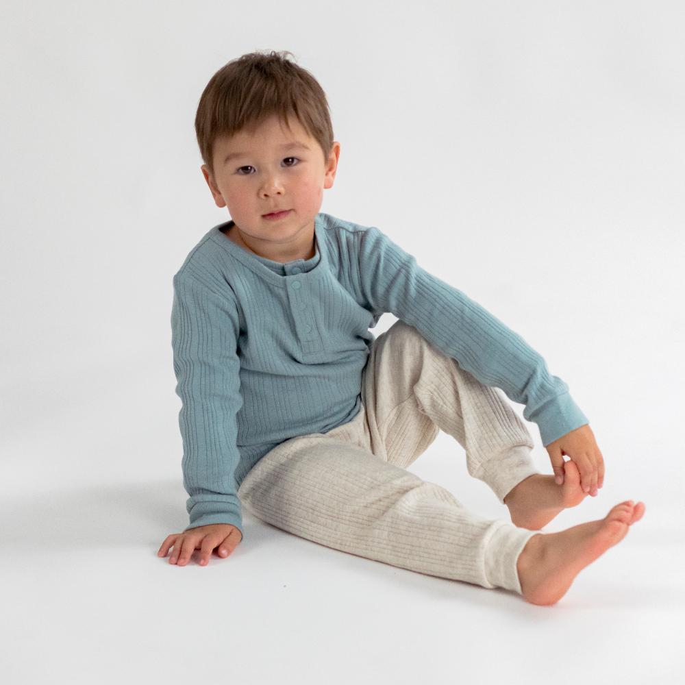 Child wearing a blue long-sleeve shirt and beige pants on a white background