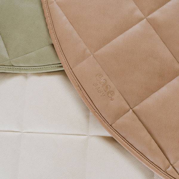Close-up of quilted baby blankets in soft neutral tones, including a tan quilted blanket with an embossed 'ease. baby.