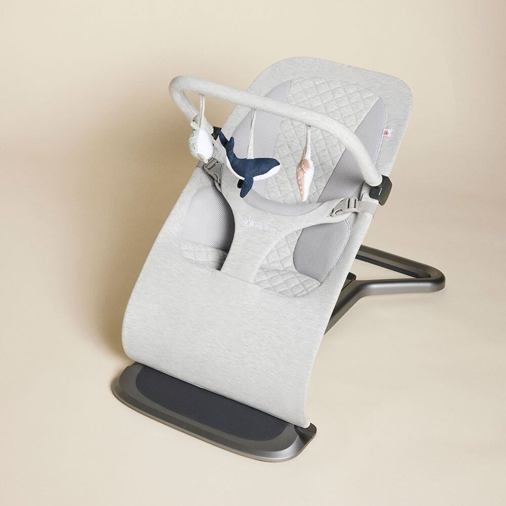 Baby bouncer with quilted design and whale illustration on a beige background