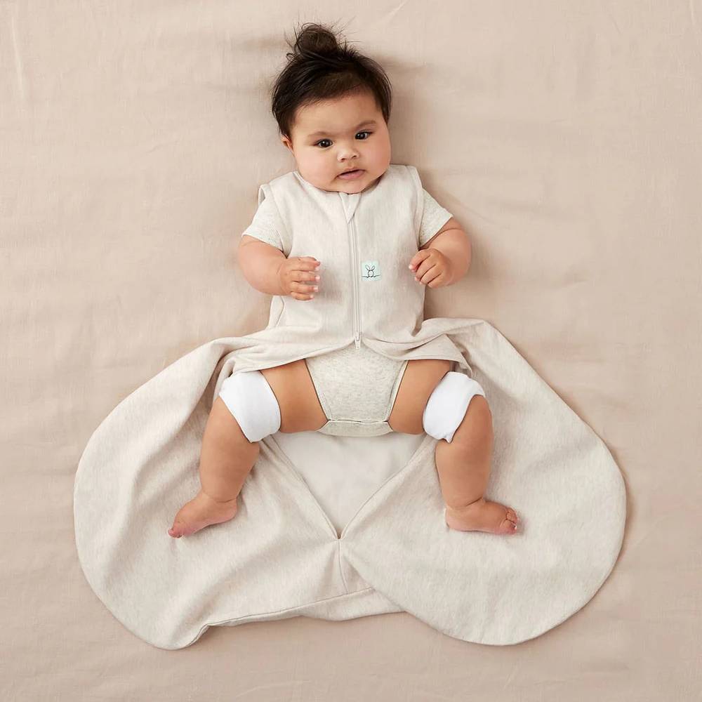 Baby lying on a beige sleep sack wearing a hip brace 