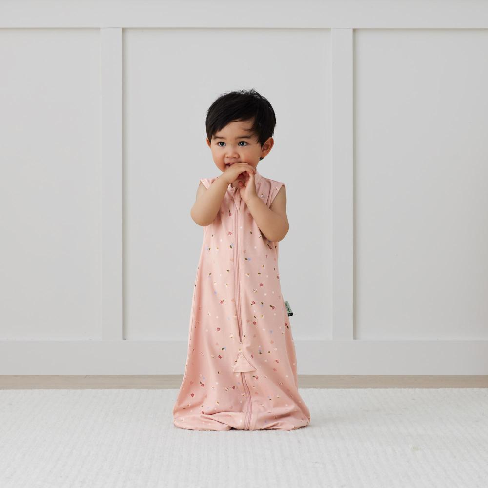 Child wearing a pink sleep sack with a white background