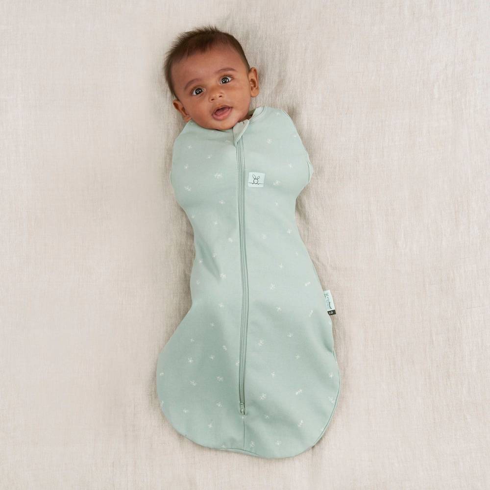Prem Baby wrapped in a light green swaddle with star pattern on a beige blanket