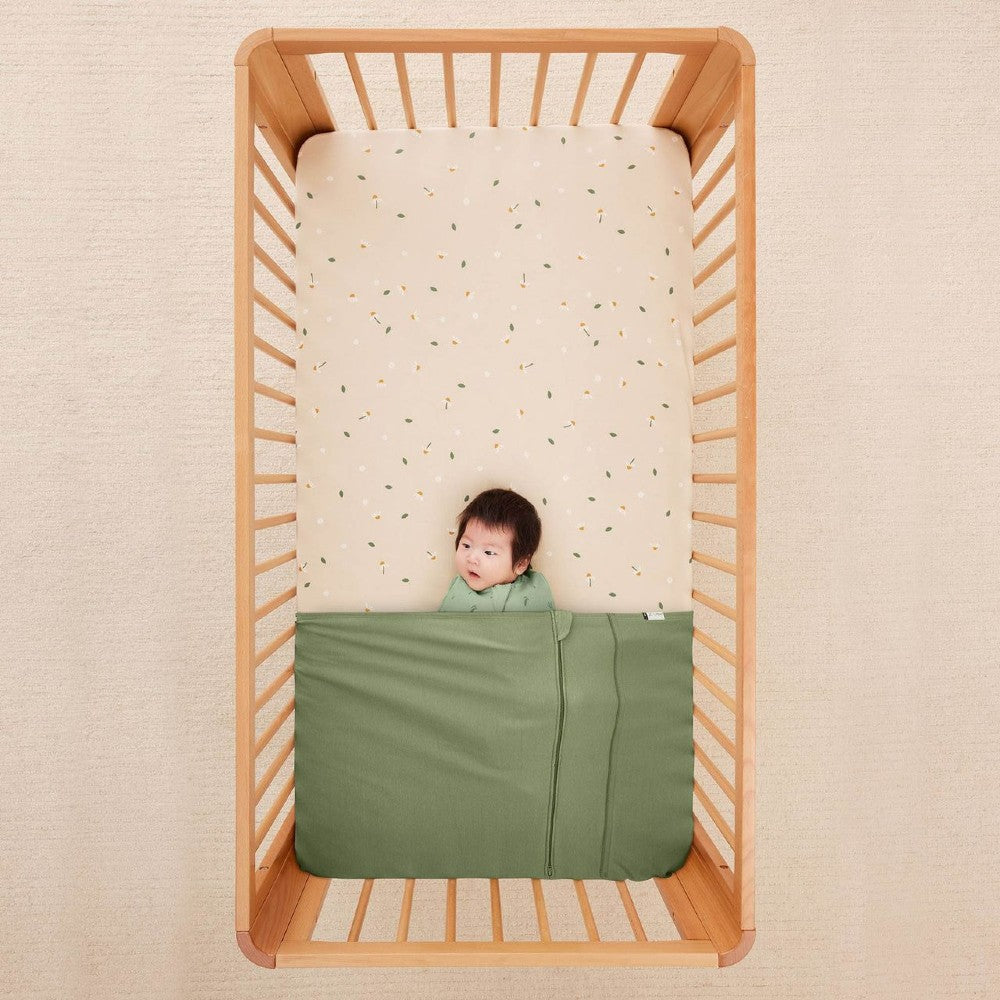 HugMe Blanket in Moss pattern on a mattress on white background