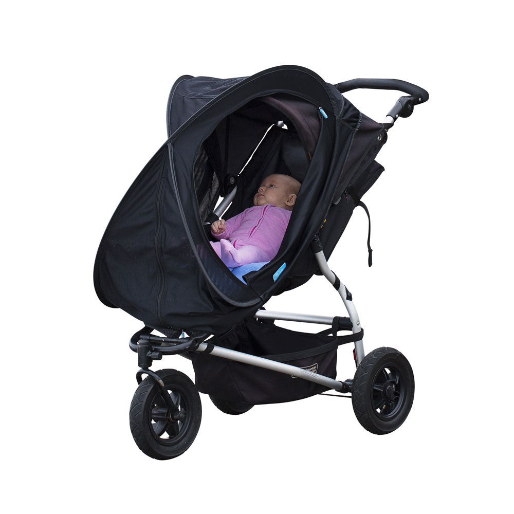 A black baby stroller with a canopy, shown with a baby inside wearing a pink outfit. The stroller has a silver frame and three black wheels, photographed against a solid white background.