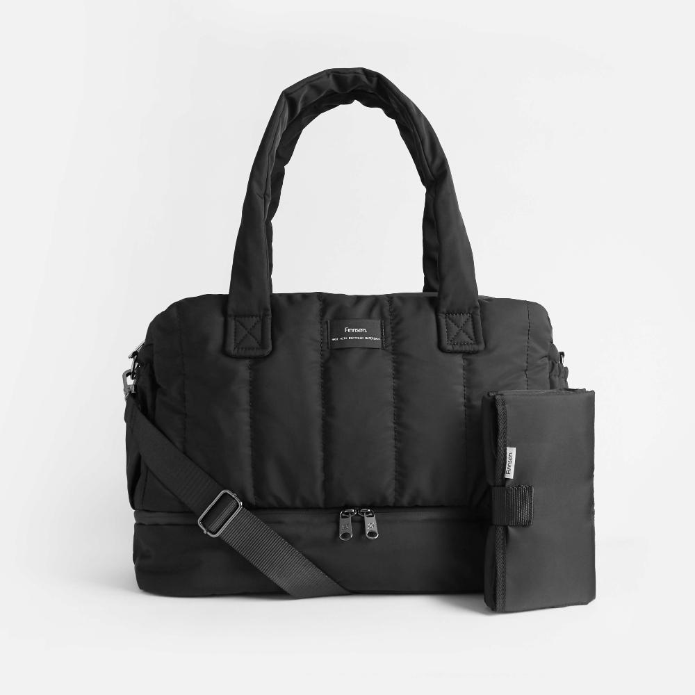 Black quilted fashion diaper bag with a change mat on a light gray background