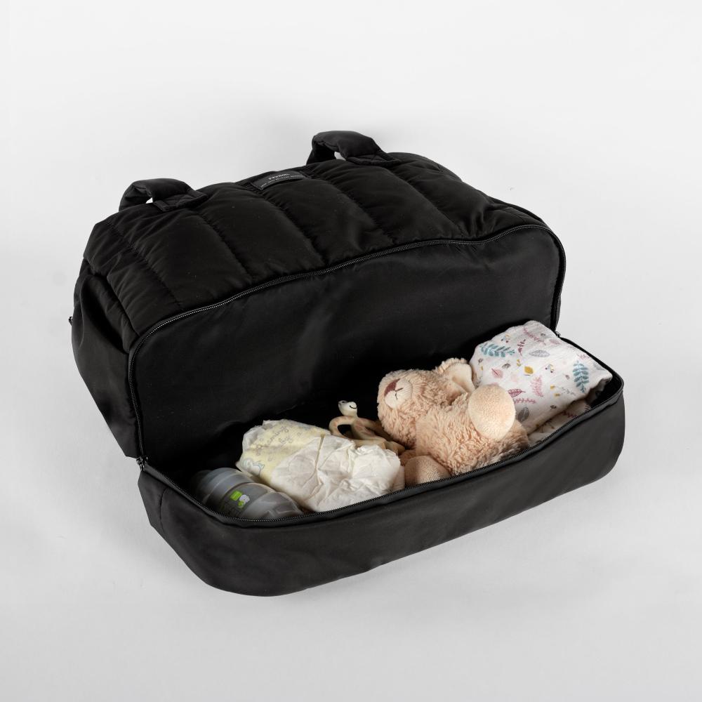Black backpack with baby items like a teddy bear and diapers on a light gray background