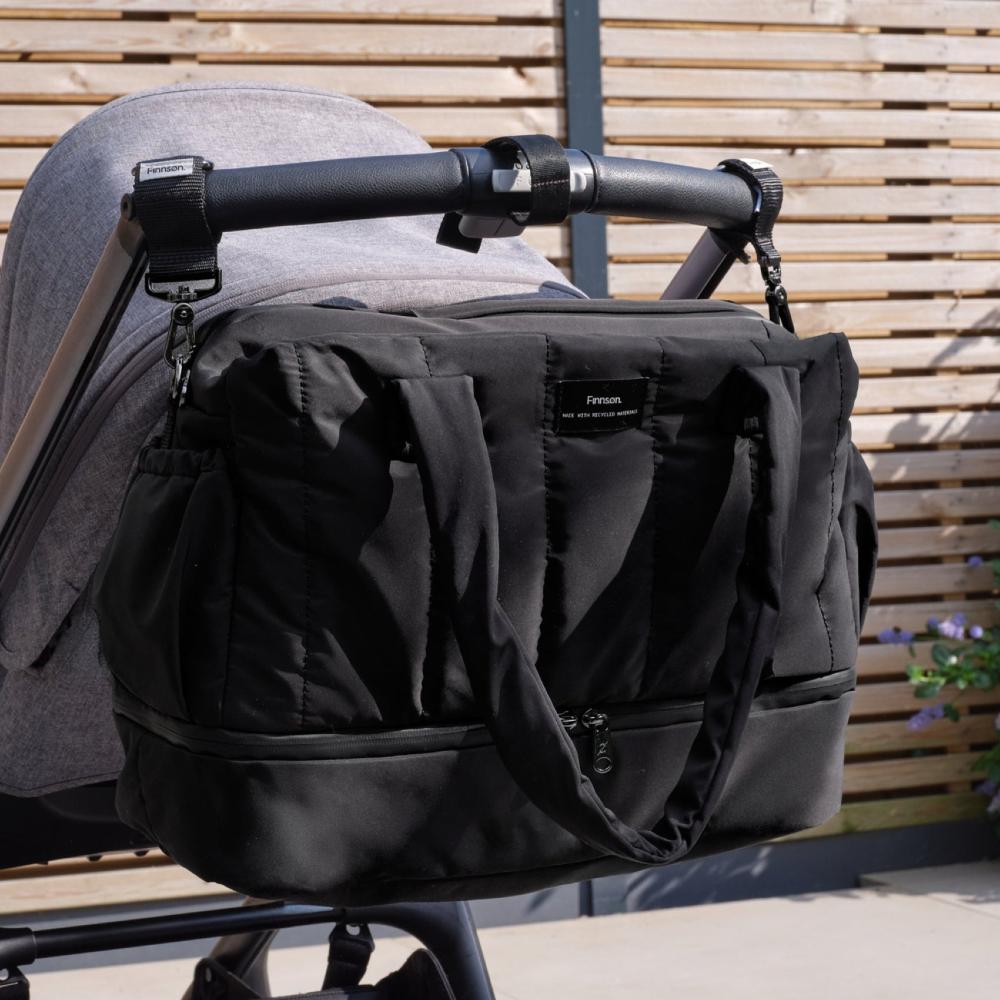High fashion black nappy bag attached to a stroller with a wooden background