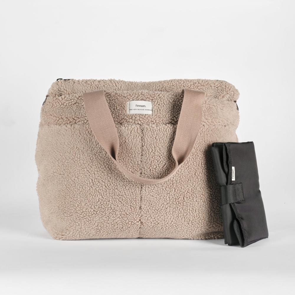 Beige sherpa tote bag with a black change mat on a light gray background