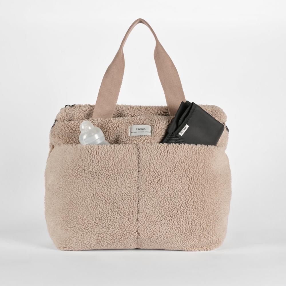 Beige sherpa tote bag with a black wallet and bottle on a white background