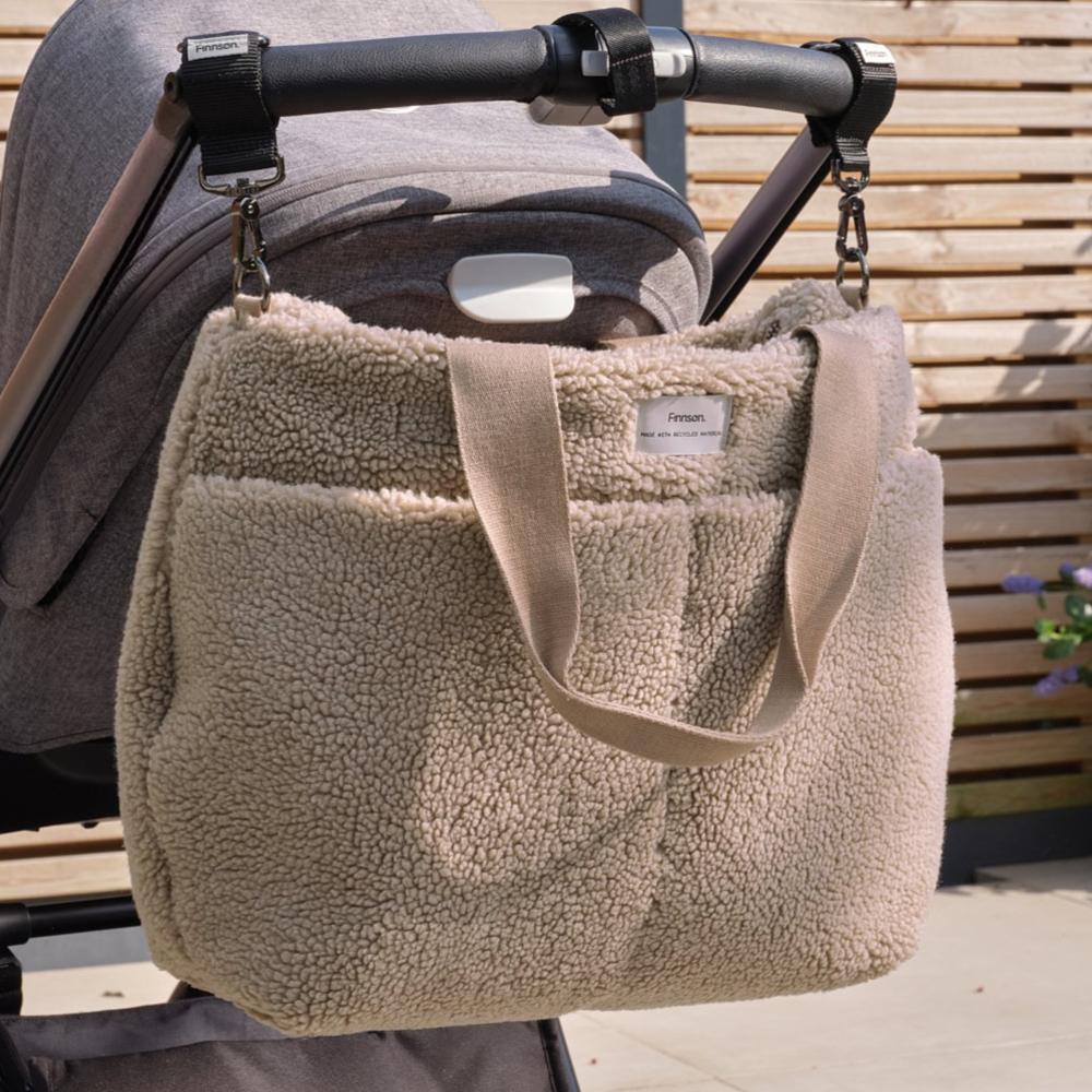 Beige Finnson sherpa bag attached to a stroller with a wooden background